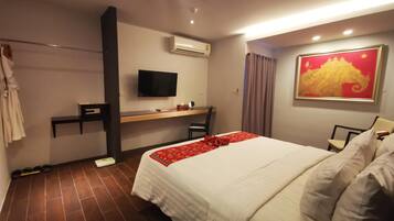 Quarto de hotel com cama, secretária, televisão e ar condicionado.