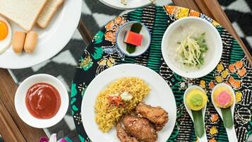 Variedad de platos que incluyen arroz, pollo y una ensalada, dispuestos sobre una bandeja con mantel estampado.