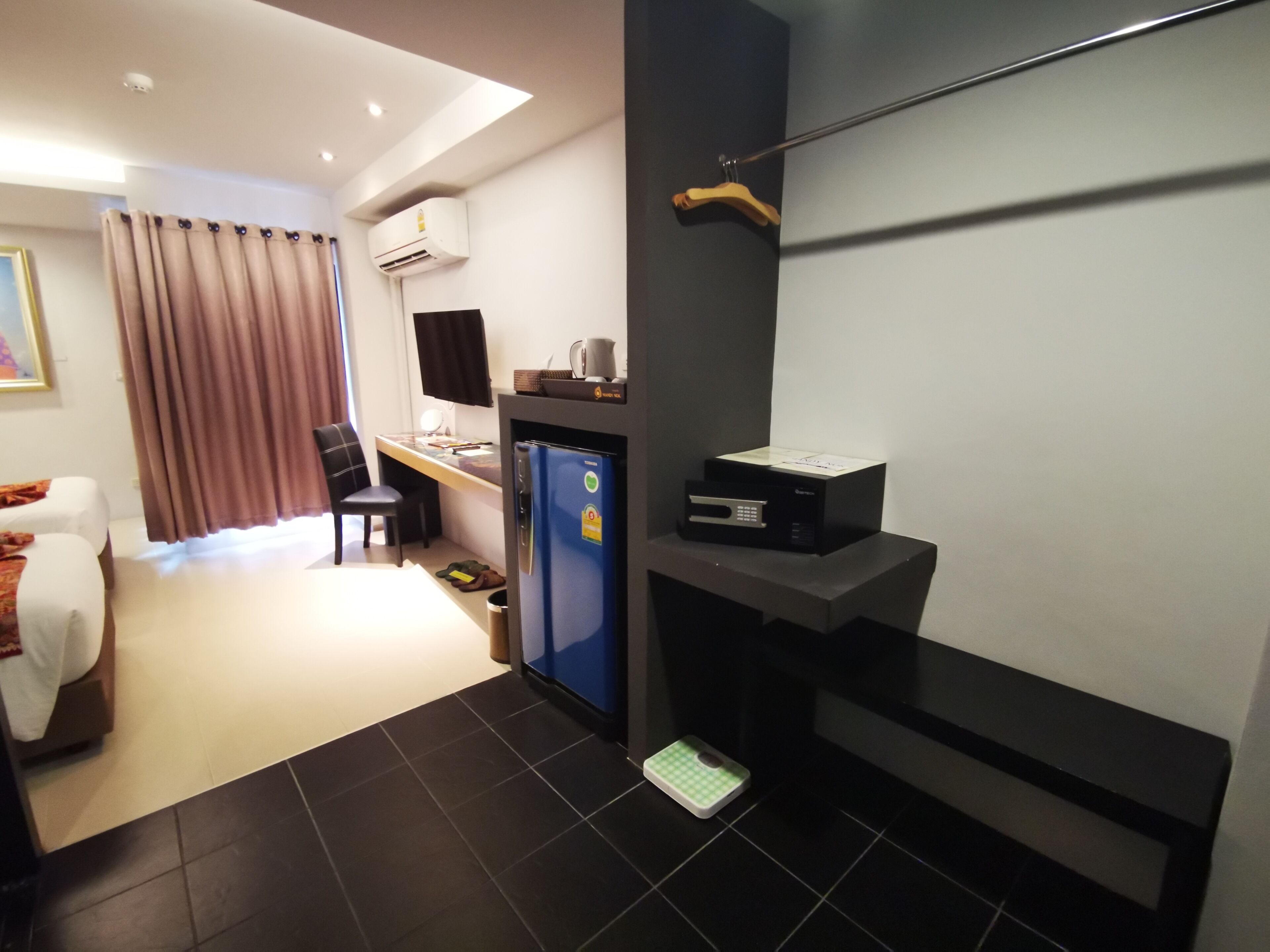 Una habitación de hotel compacta con cama, escritorio, refrigerador y una pequeña kitchenette.