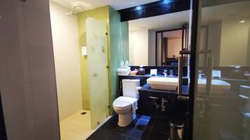 Un baño moderno con cabina de ducha de vidrio, inodoro, lavamanos y espejo.