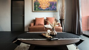 Una sala de estar moderna con un sofá de cuero marrón, una mesa redonda de centro con objetos decorativos y un cuadro enmarcado sobre el sofá.