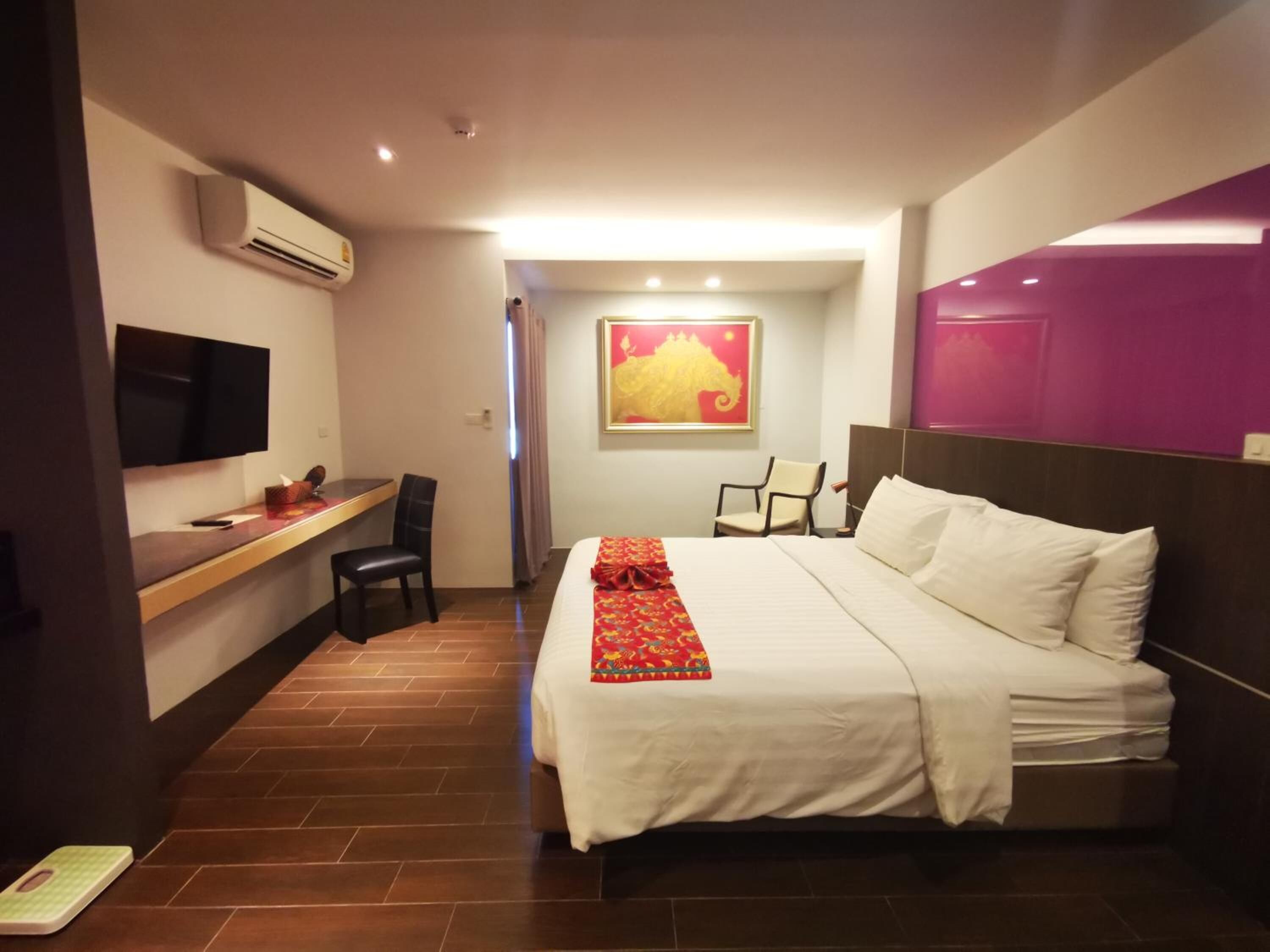 Ein Hotelzimmer mit einem Bett, einem Schreibtisch, einem Sessel, einem Fernseher und einer Klimaanlage.