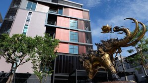 Un edificio moderno con un letrero que dice "MANDY NOK" y una estatua dorada al frente.