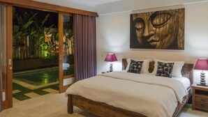 Un dormitorio con una cama grande, cabecera de madera, un cuadro en la pared y una puerta corrediza de vidrio que da a una zona de piscina.