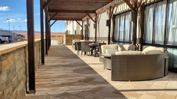 Un espacio de estar al aire libre cubierto con paredes de piedra, muebles de mimbre y vistas al paisaje desértico.