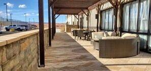 Un espacio de estar al aire libre cubierto con paredes de piedra, muebles de mimbre y vistas al paisaje desértico.