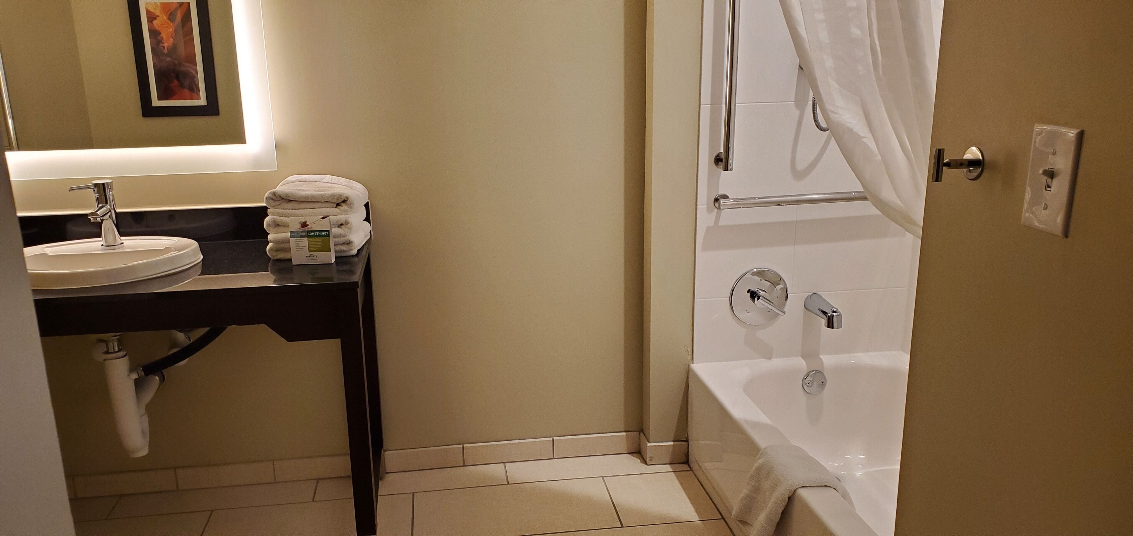 A bathroom with a sink, mirror, towel rack, and bathtub.