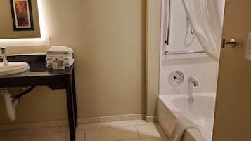 A bathroom with a sink, mirror, towel rack, and bathtub.