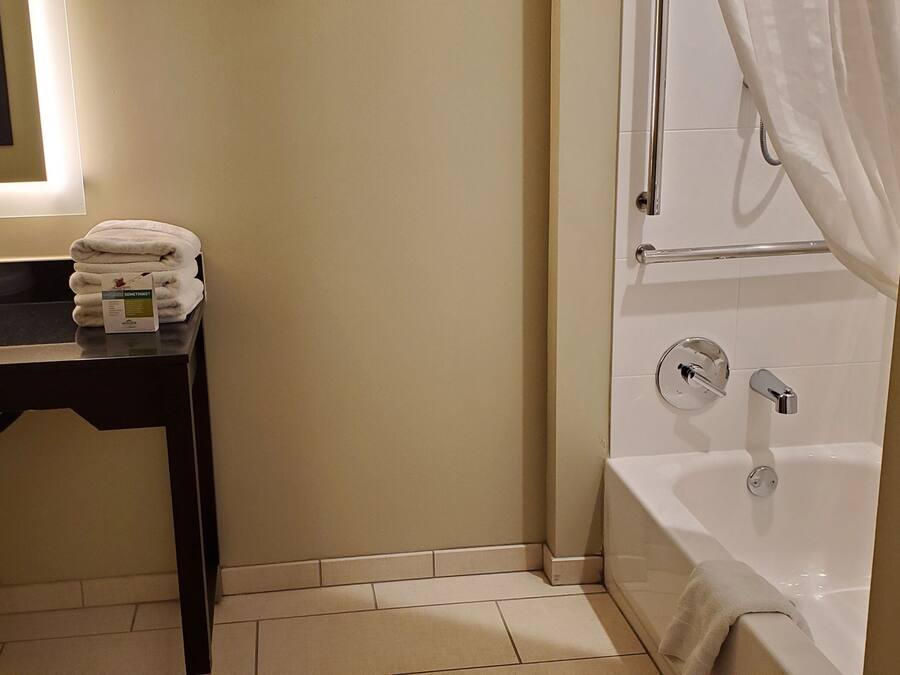 A bathroom with a sink, mirror, towel rack, and bathtub.