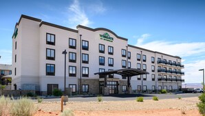 Un hotel de varios pisos con fachada plana, ventanas amplias y un acceso cubierto.