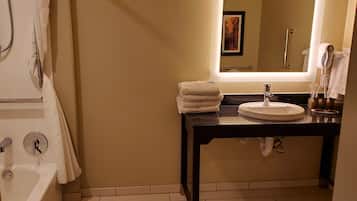 Un baño con bañera, lavabo con espejo y perchero.