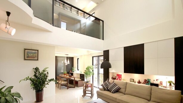 A spacious living area with a high ceiling, a sofa, a coffee table, and a dining area. - Penghu 123 V-Stone Inn (Magong)