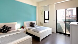 A modern bedroom with two beds, a large window, and a view of buildings. - Penghu 123 V-Stone Inn (Magong)