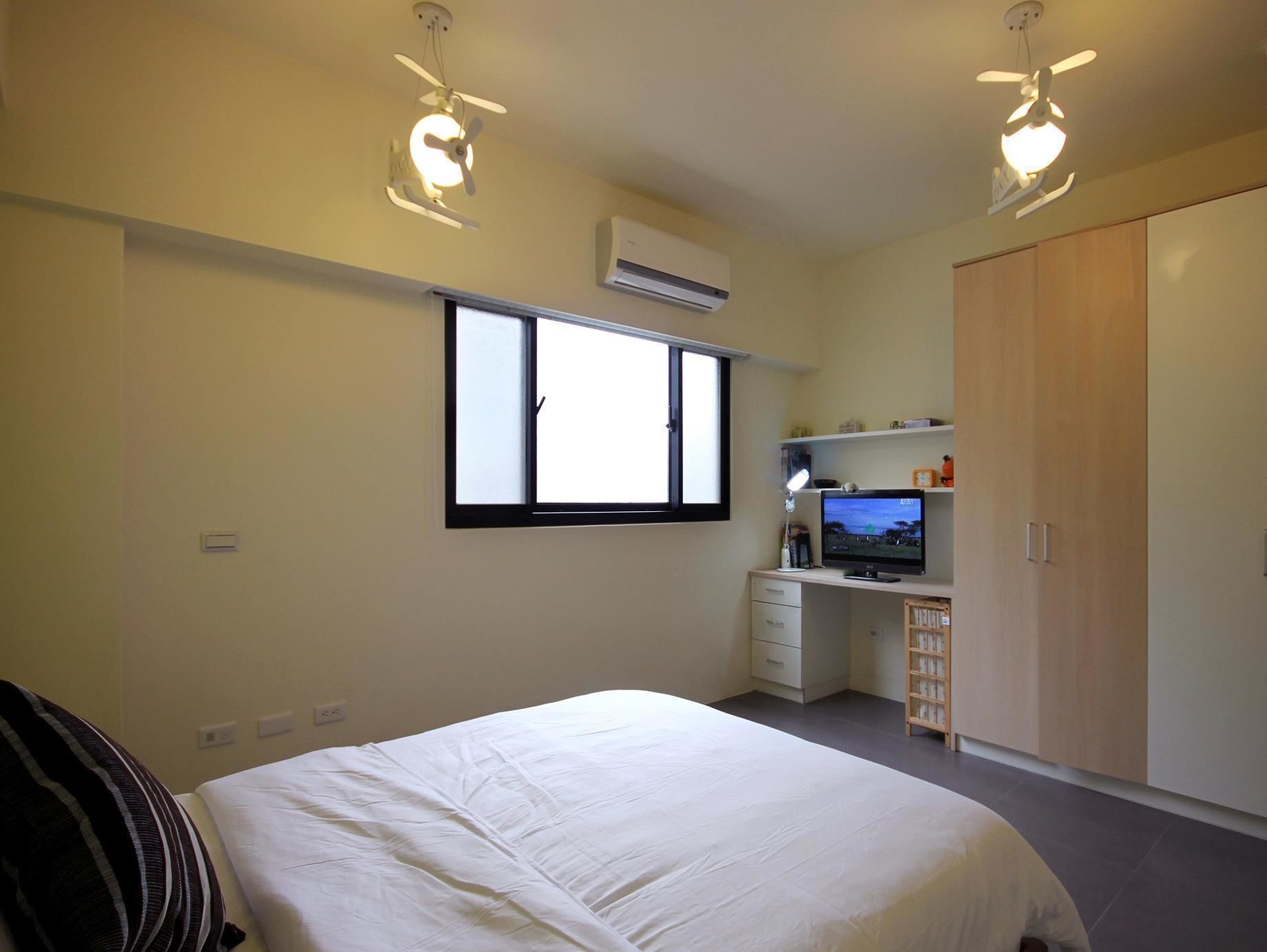 Een slaapkamer met een bed, een bureau met computer, een kledingkast en een raam.
