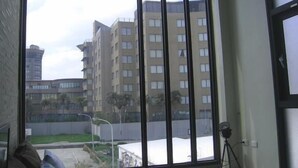 A room with a large window, a bed with striped bedding, and a tripod lamp. - Penghu 123 V-Stone Inn (Magong)
