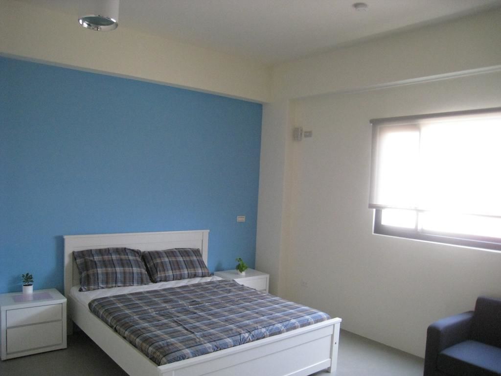 A bedroom with a bed, nightstands, a window, and a chair.