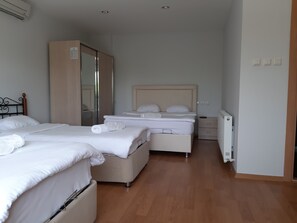 Une chambre d’hôtel avec deux lits, une armoire, une table de chevet, un radiateur et un luminaire au plafond.