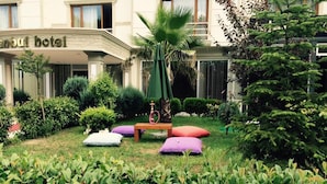 A hotel courtyard with a palm tree, a wooden bench, and colorful cushions. - The Hotel Sapanca (Sapanca)