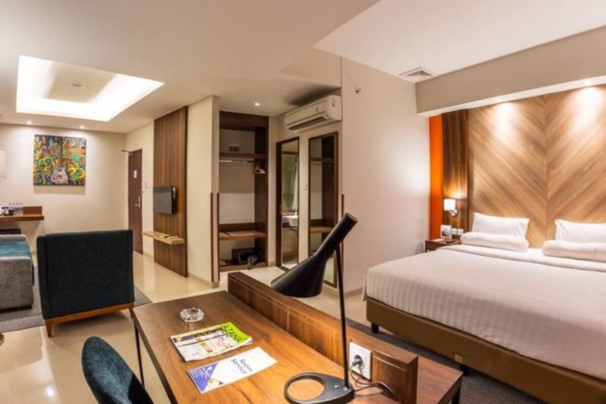 Una habitación de hotel con cama, escritorio, silla, televisión y armario.