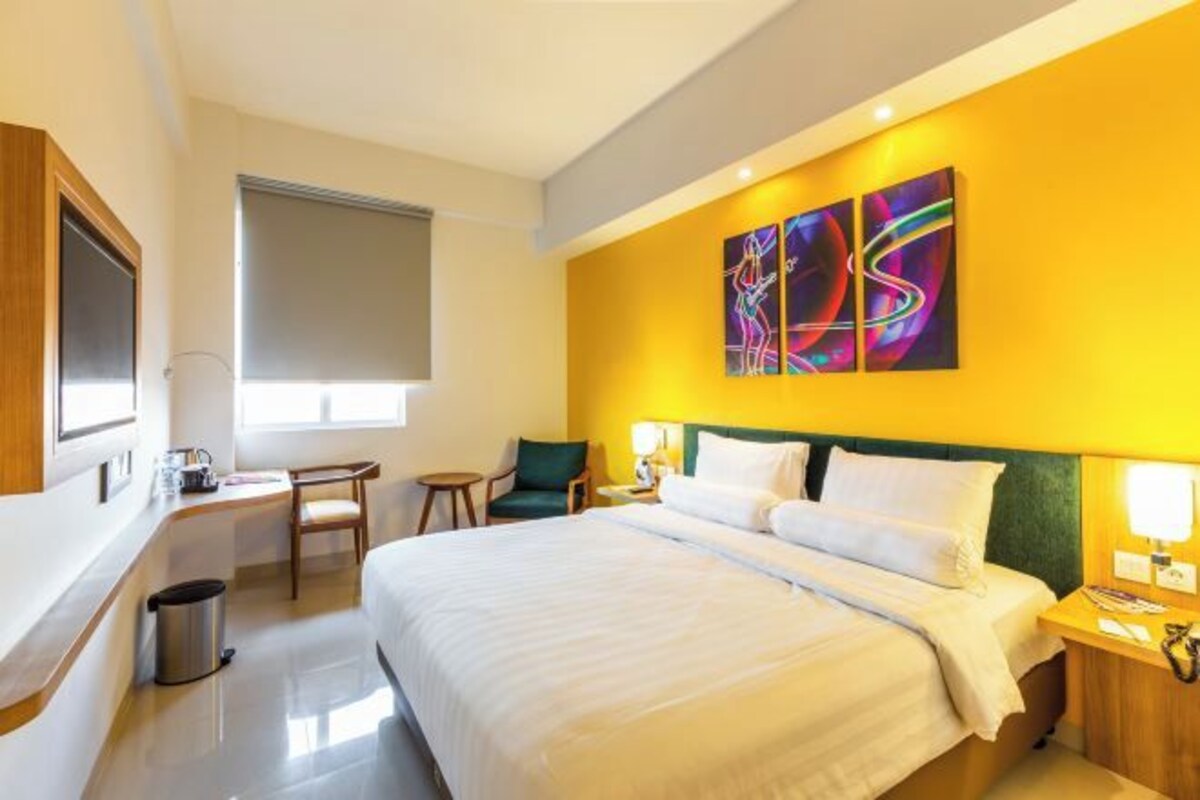 Una habitación de hotel con una cama grande, un escritorio, una silla y una ventana con persiana.