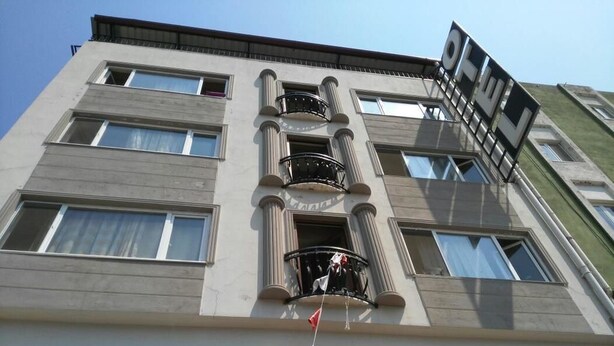 En bygning med flere etager, en central balkon, store vinduer og et flag.