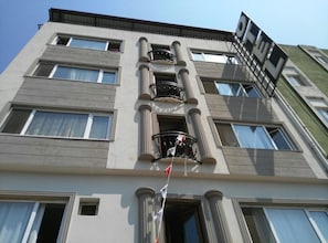 Un edificio de varios pisos con un balcón central, ventanas amplias y una bandera.
