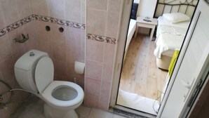 Et lille badeværelse med toilet, håndvask og spejl.