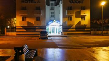 Entrada de hotel con un coche estacionado frente a él.
