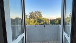 A balcony with a tiled floor and a view of trees and buildings. - Hotel Vajont (Vajont)