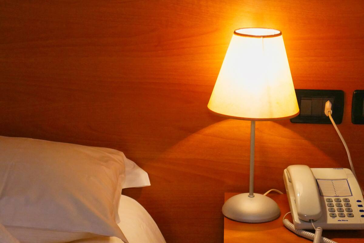 A hotel room with a bed, a bedside lamp, and a telephone.