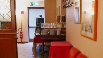 A hotel lobby with a red seating area, a reception desk, and a fire extinguisher.