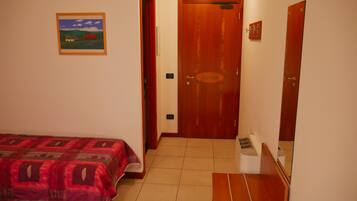 A bedroom with a bed, a door, a small window, and a wall-mounted picture.