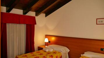 A hotel room with a wooden headboard, a bed with a floral bedspread, a nightstand with a lamp, and a red curtain.
