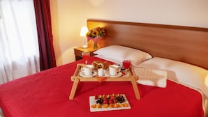 A neatly made bed with a red bedspread, a tray with breakfast items, and a fruit plate. - Hotel Vajont (Vajont)