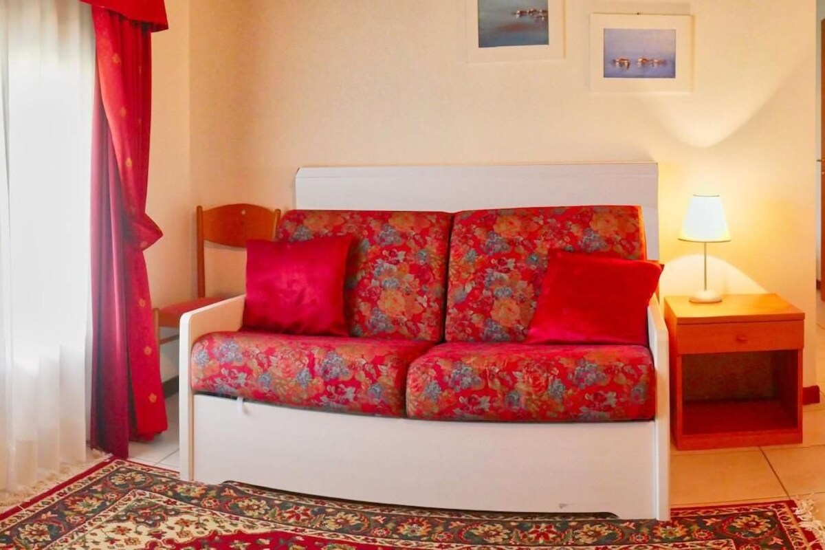 A room with a bed, a nightstand, a lamp, a chair, and a rug.
