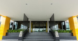 A modern building entrance with a staircase, glass doors, and yellow and black color scheme. - Seven Bee Boutique Hotel (Surin)