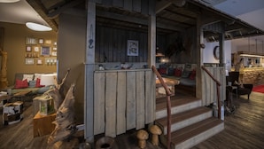 Un interno rustico con travi in legno, una scala e un'accogliente zona salotto con cuscini.