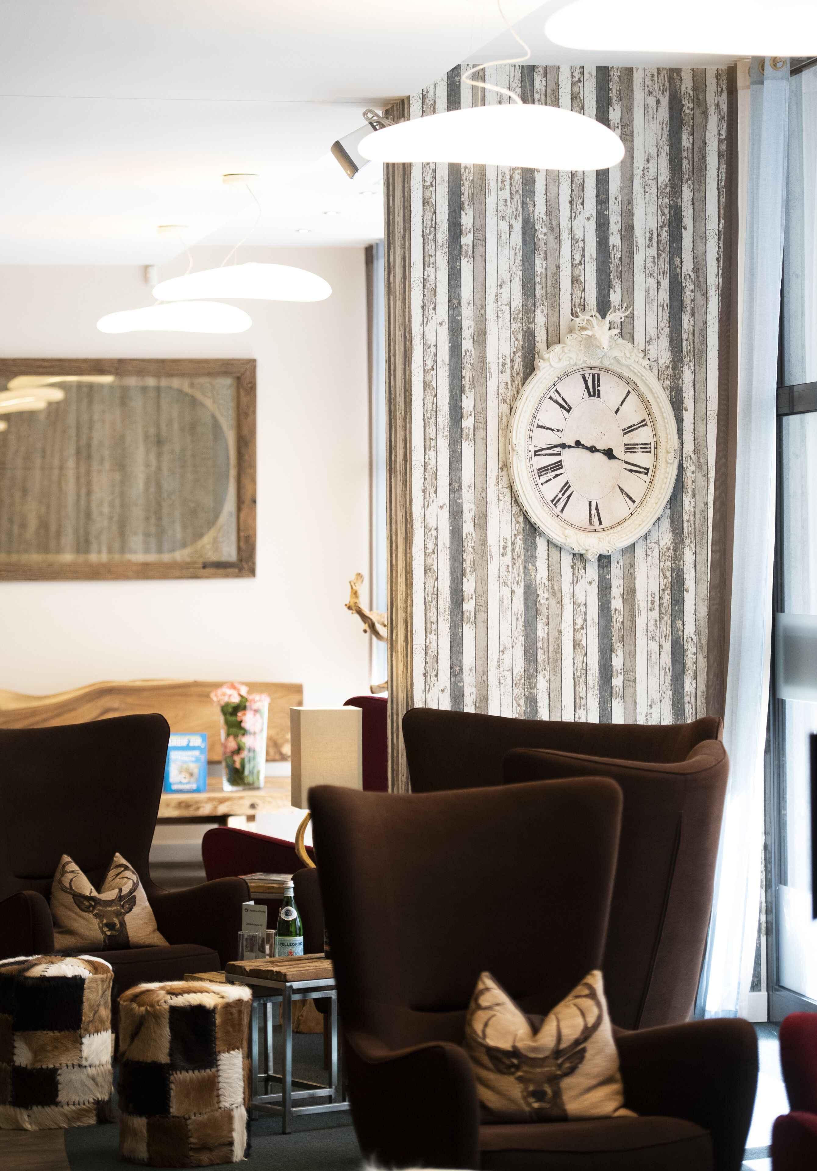 Ein Zimmer mit einer großen Wanduhr, einem spiegelnden Wandbild mit Holzrahmen und einer modernen Leuchte.