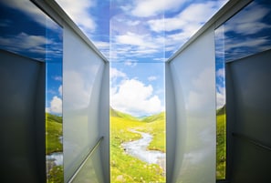 Een kamer met een groot raam, met uitzicht op een groene vallei en een rivier.