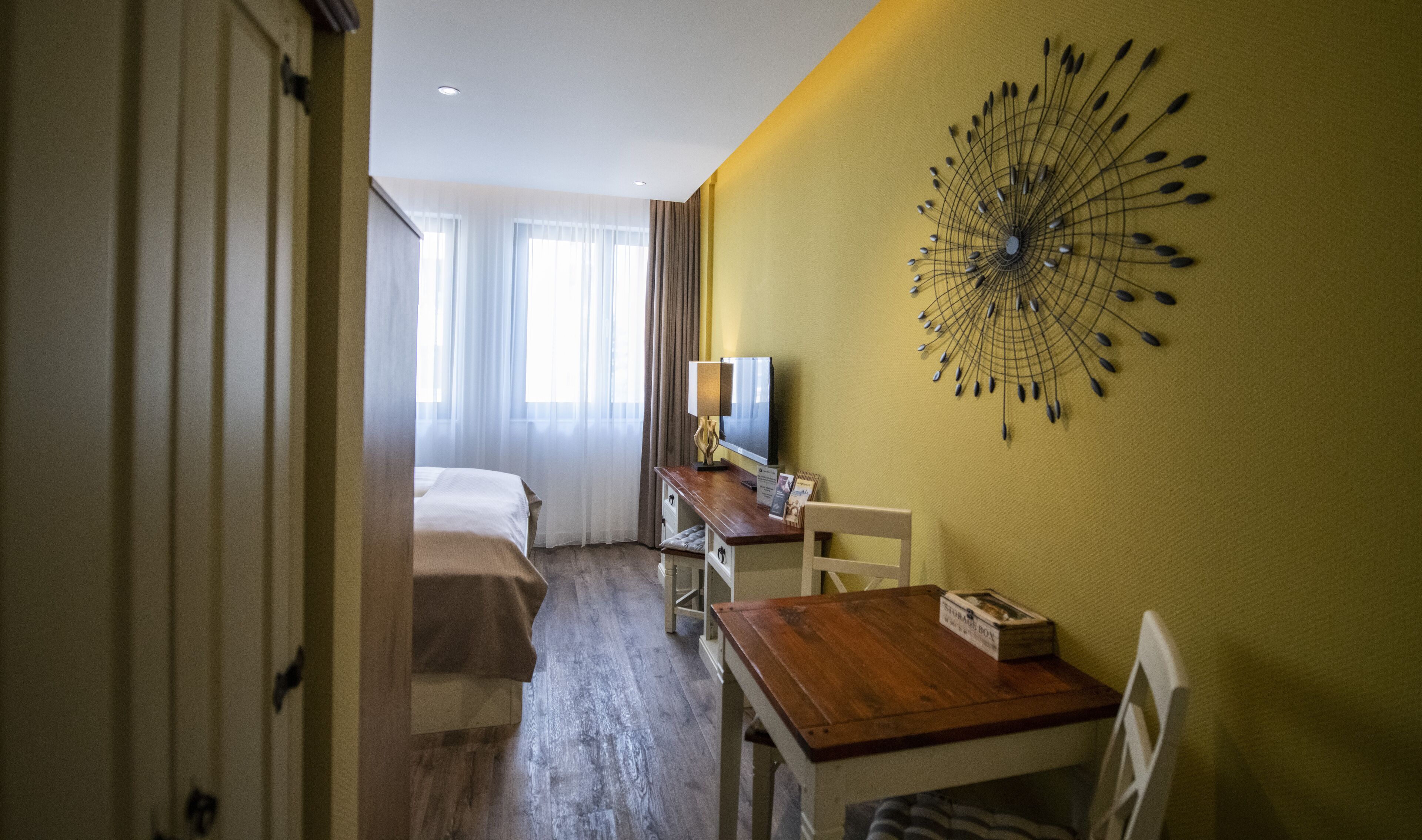 A hotel room with a bed, a desk with a chair, a television, and a wall decoration.