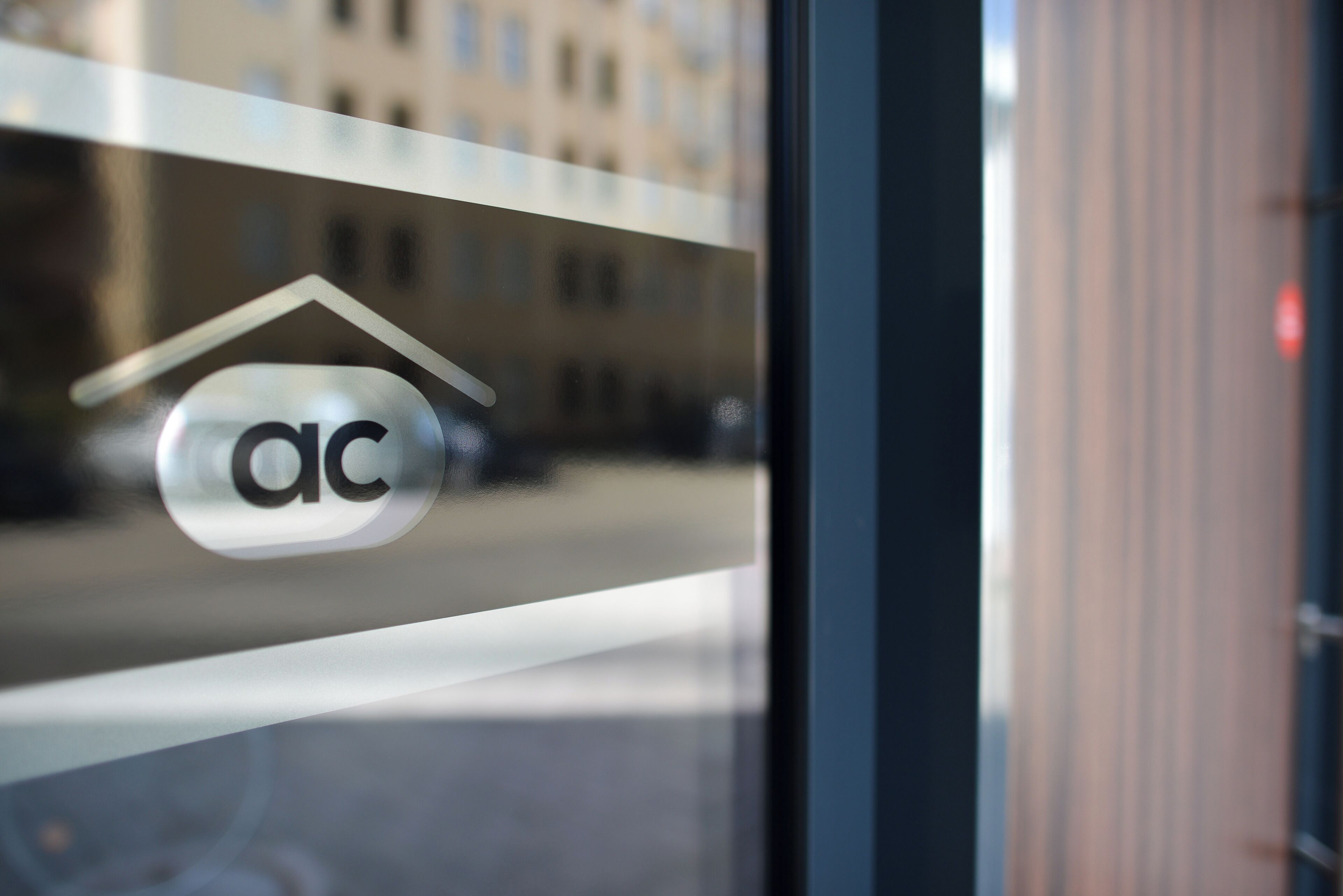Une vitre avec un logo et le reflet d’un bâtiment.