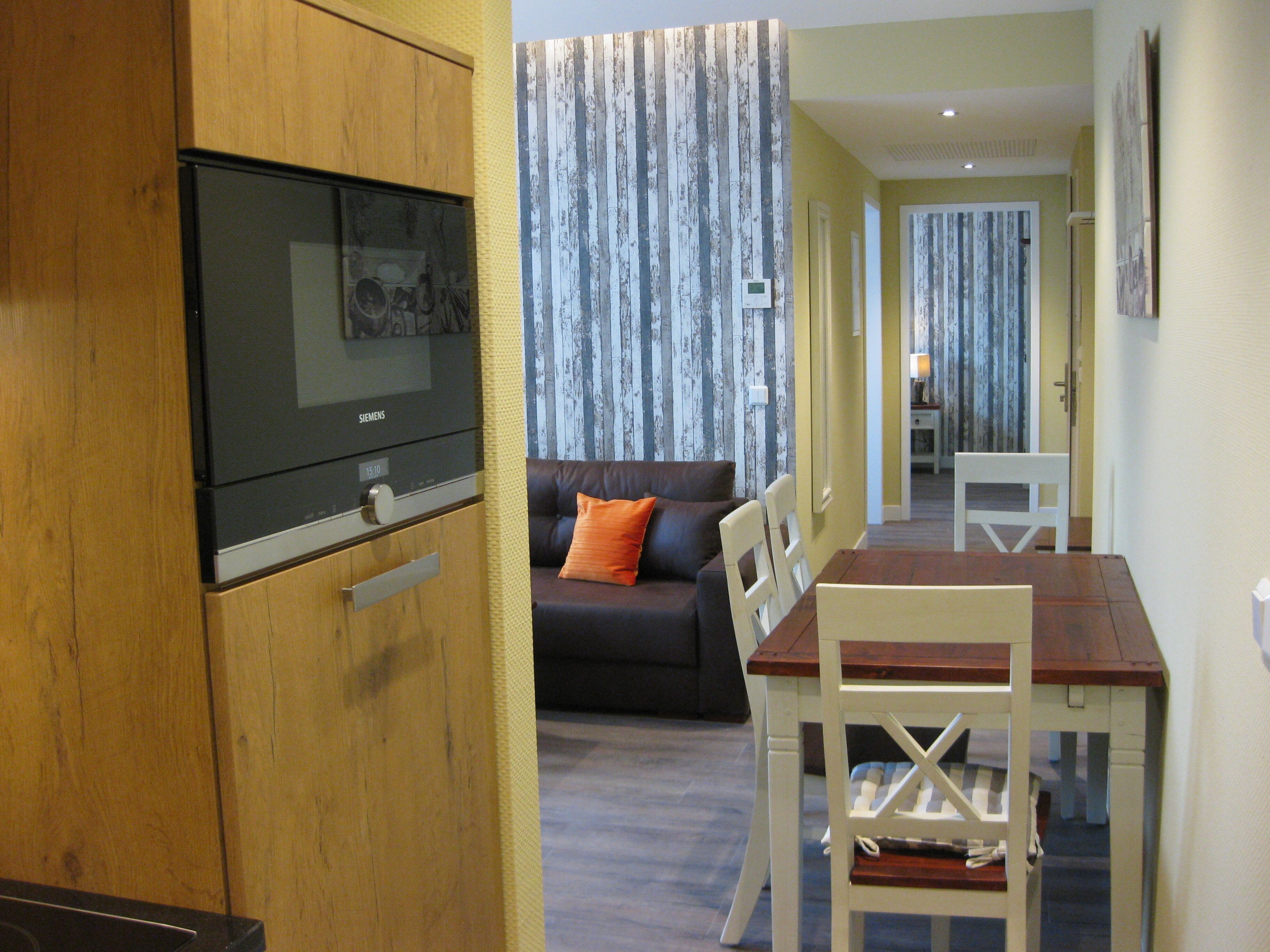 A compact living space with a kitchenette, a sofa, a dining table, and a TV.