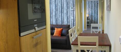 A compact living space with a kitchenette, a sofa, a dining table, and a TV.