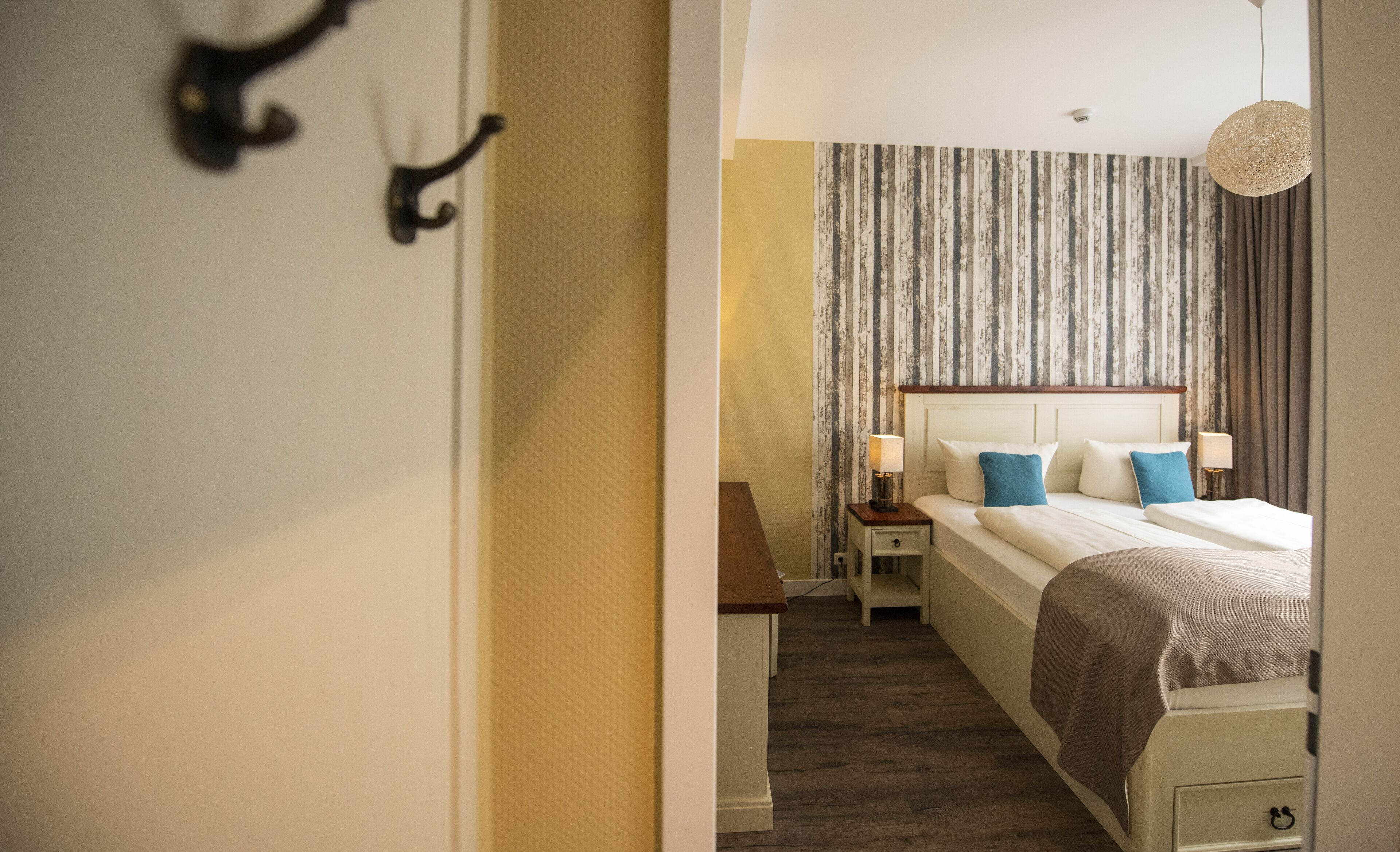 Habitación de hotel con cama, mesitas de noche y una lámpara colgante.