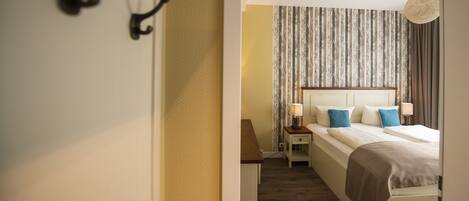 Habitación de hotel con cama, mesitas de noche y una lámpara colgante.