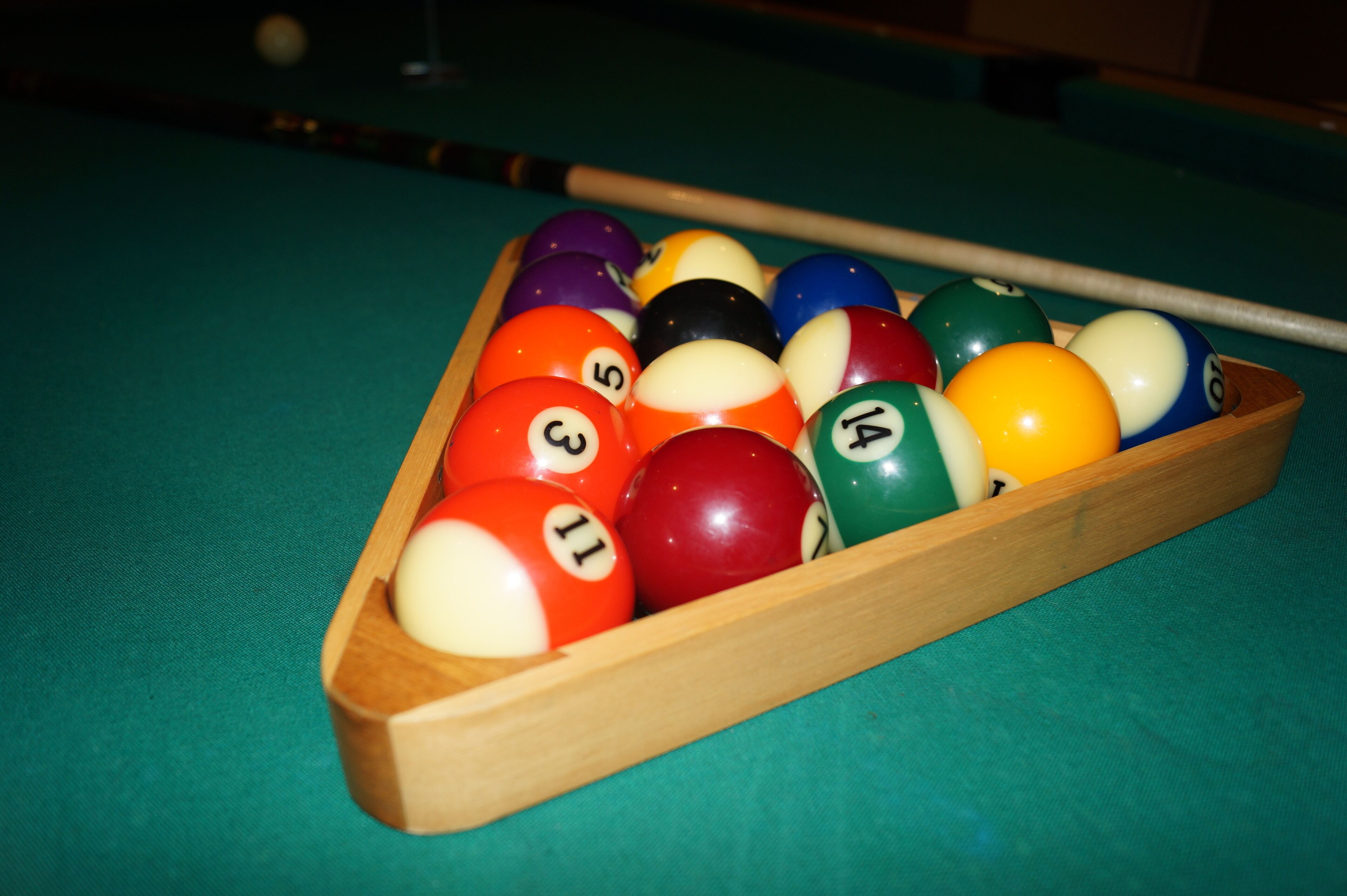 A pool table with a wooden rack holding numbered billiard balls.