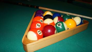 A pool table with a wooden rack holding numbered billiard balls.