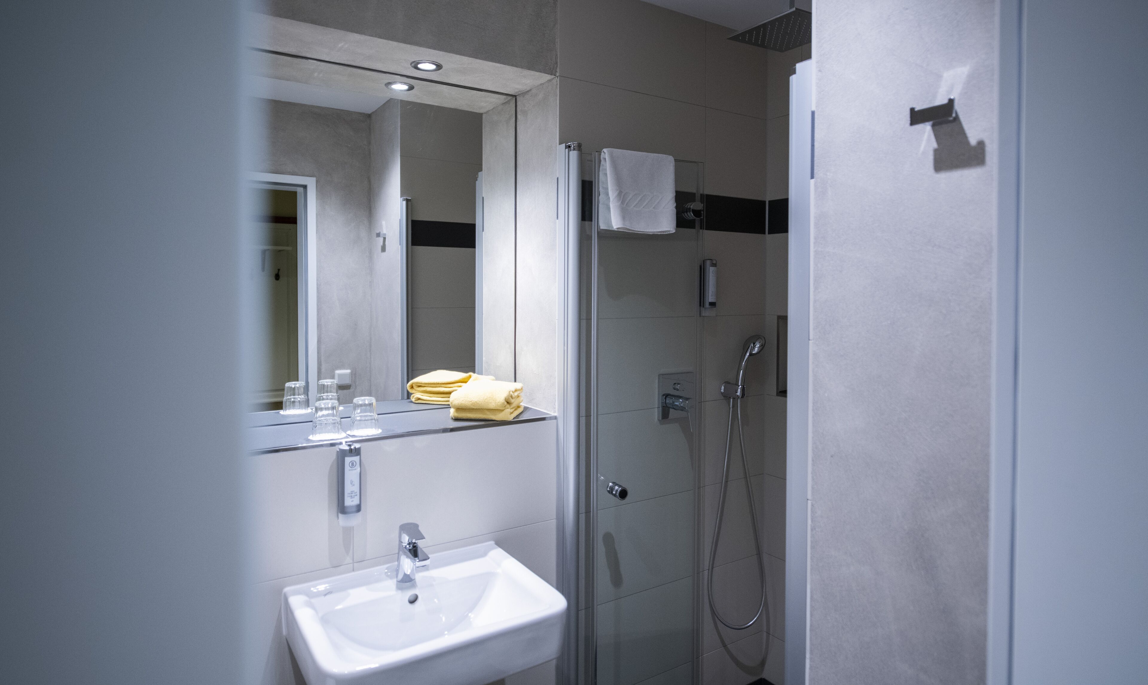 A modern bathroom with a sink, mirror, and shower.