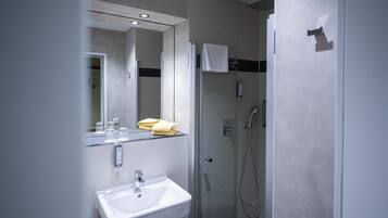 A modern bathroom with a sink, mirror, and shower.