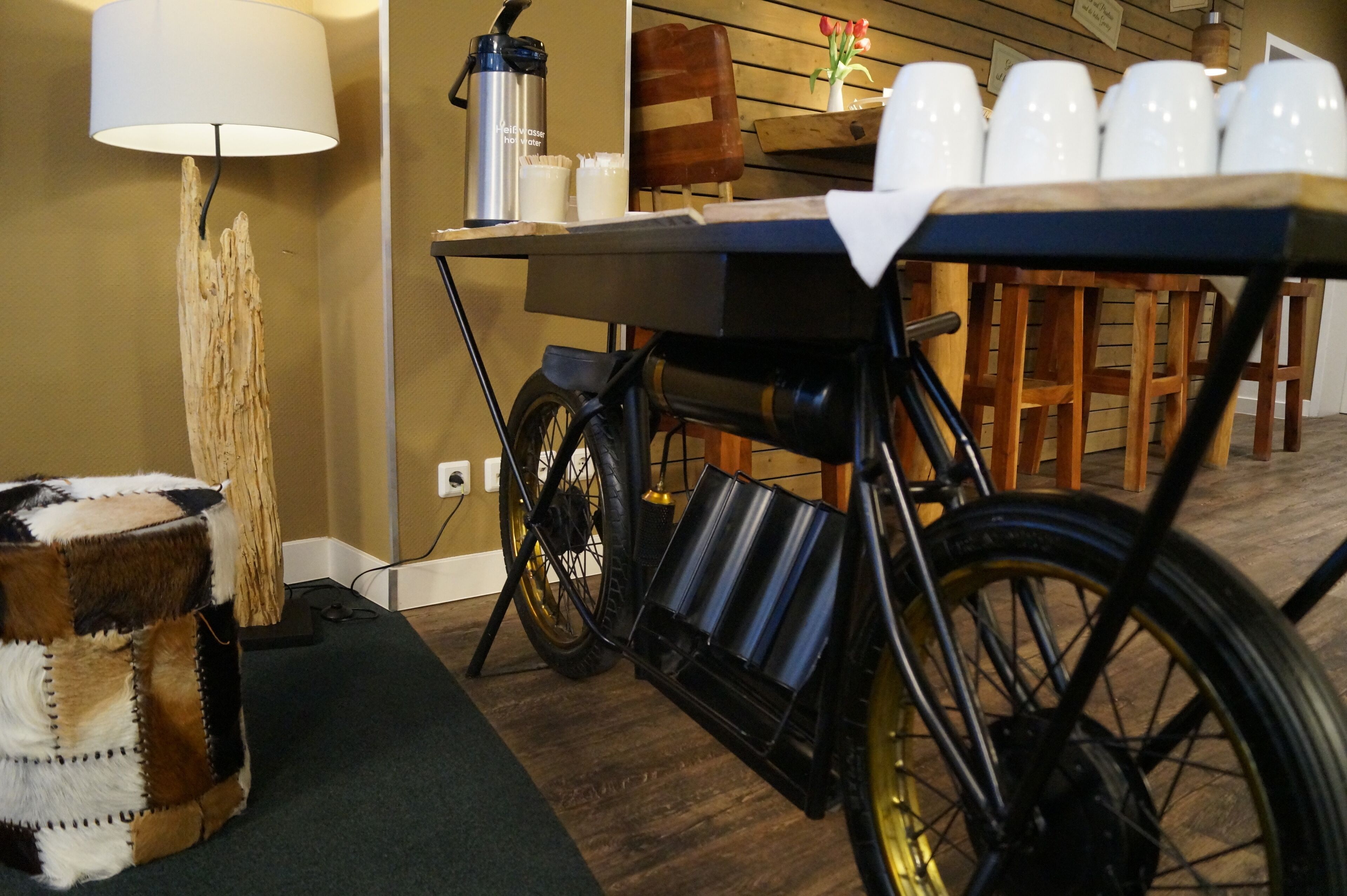 Un comedor con una mesa dispuesta para seis personas, una bicicleta y una lámpara.